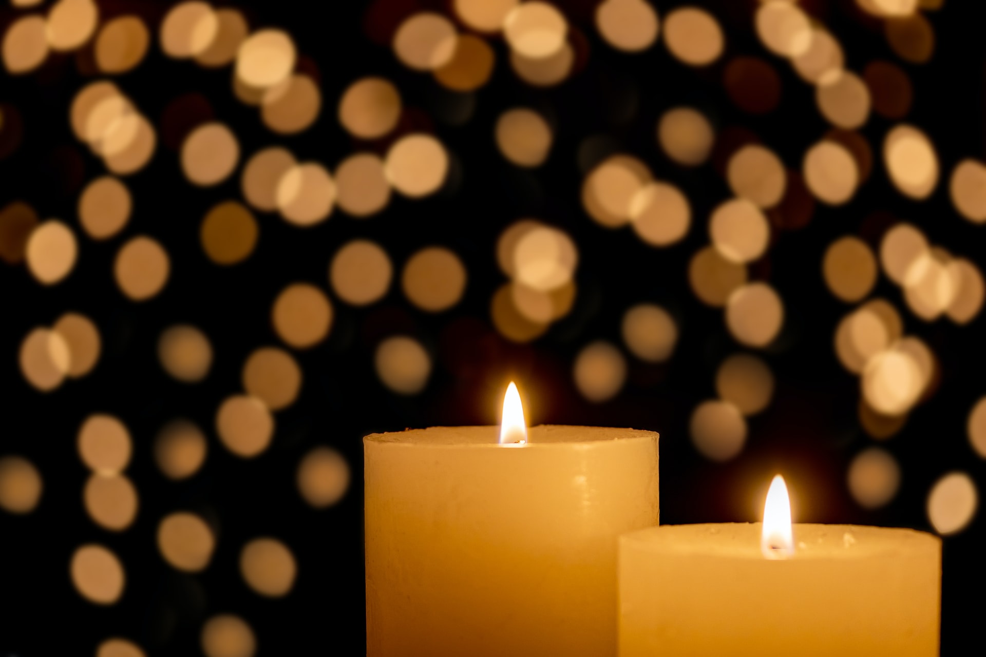 Two lit candles with spots of light in the background