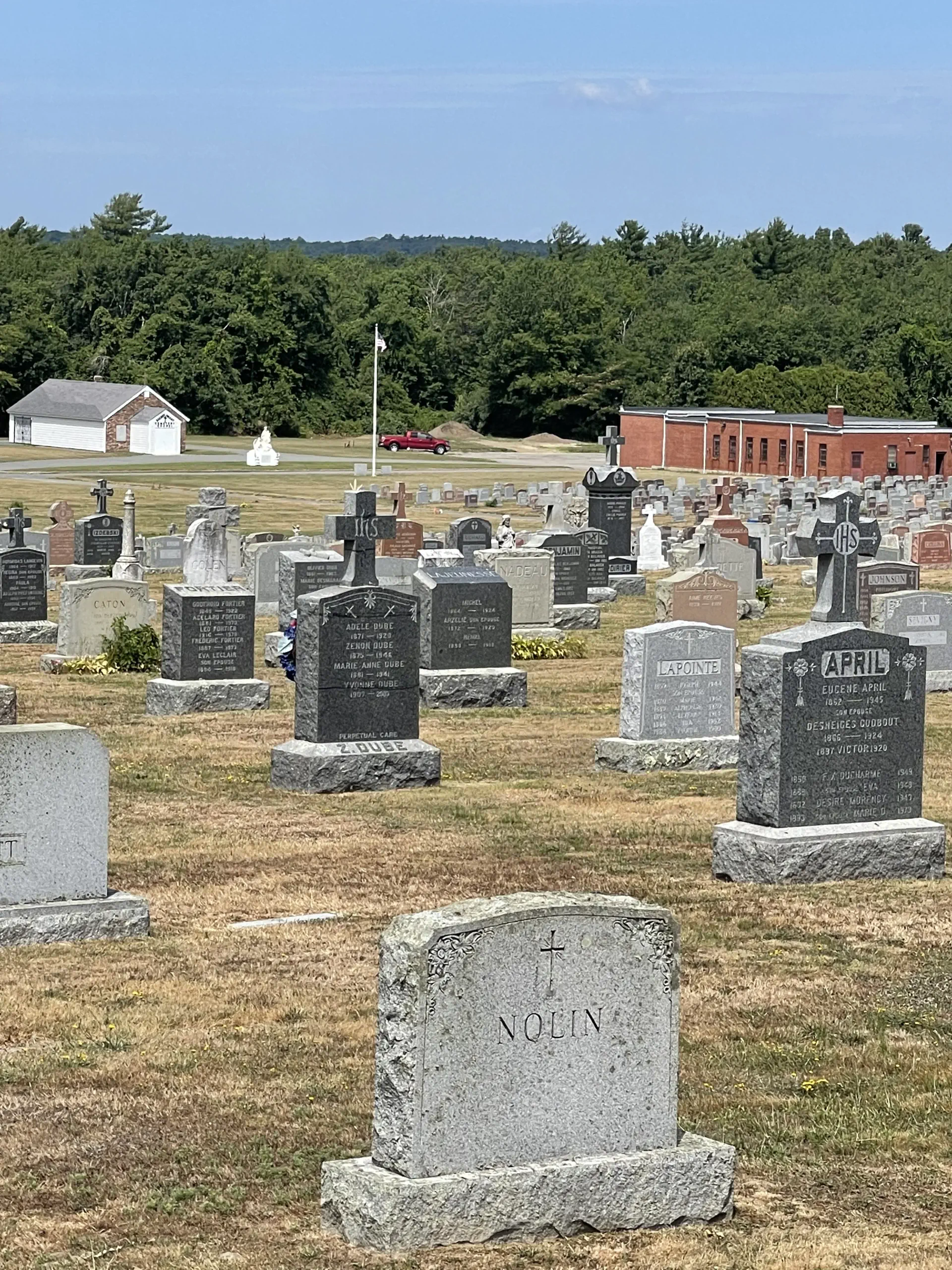 Obelisk and other headstones under a blue sky and sunshine.