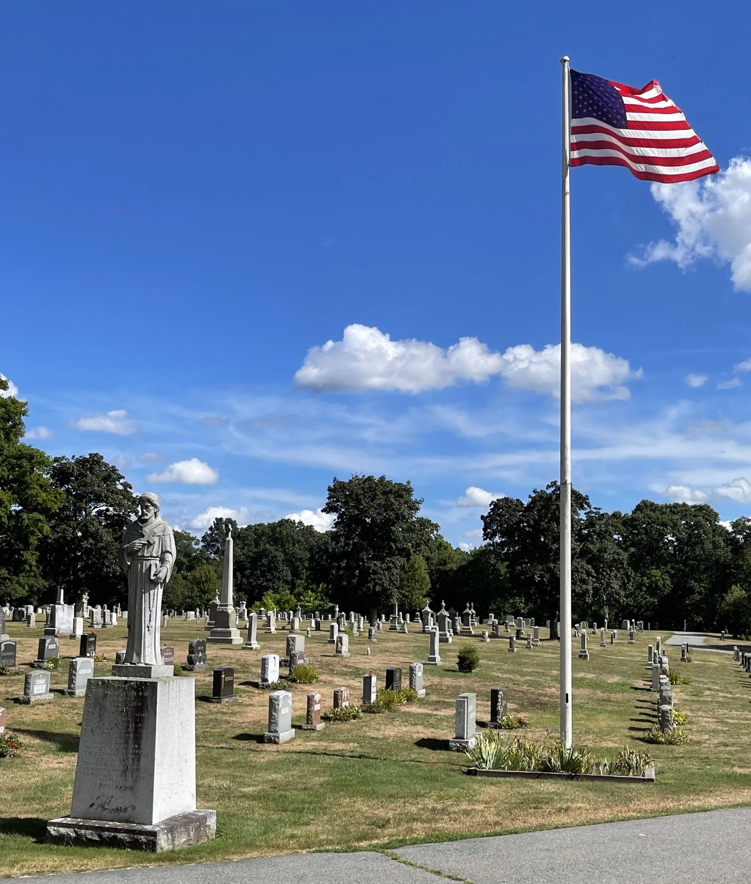 Blue sky with American flag flying high in the cemetery
