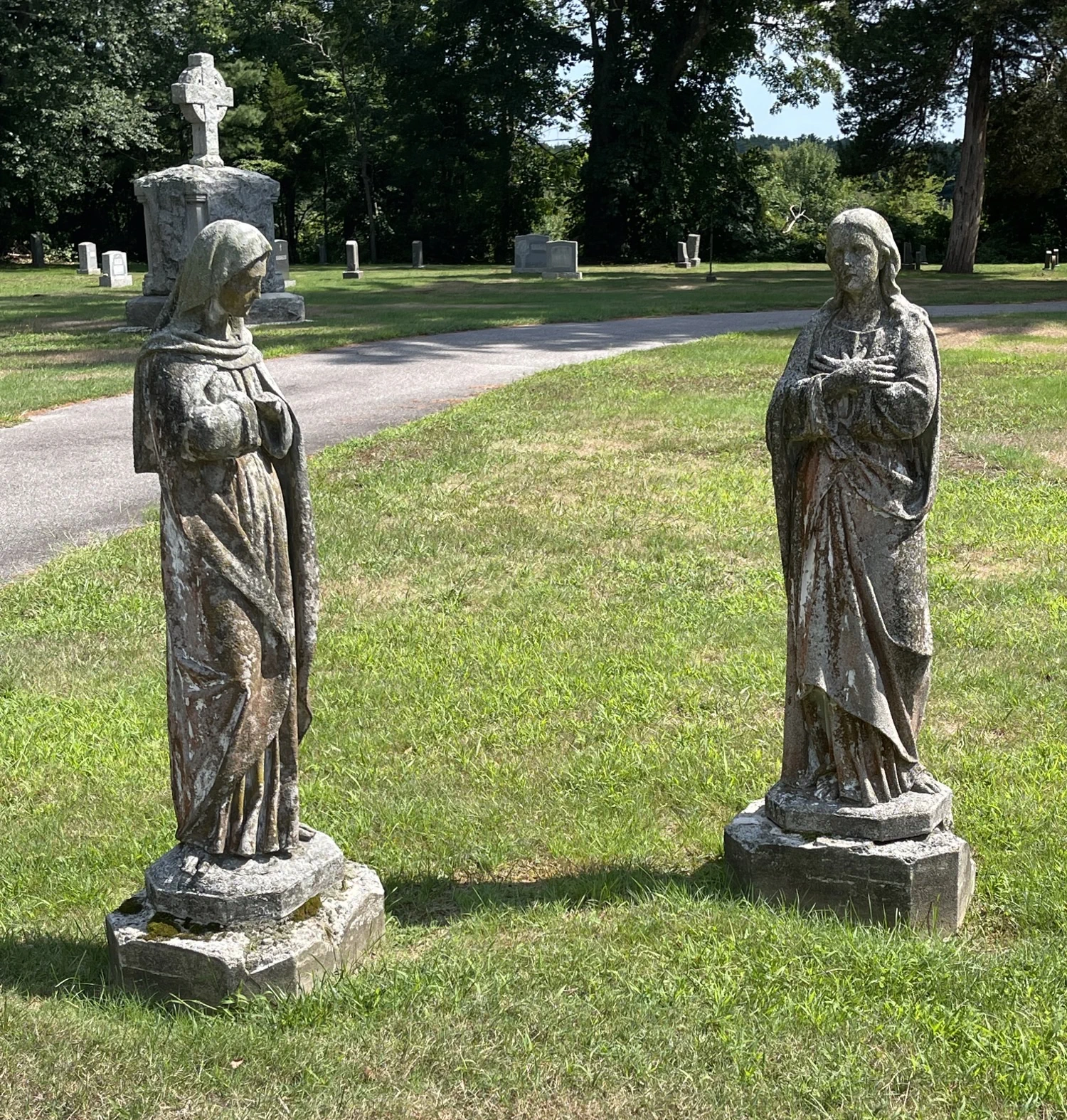 Statues of two figures near a path in the cemetery