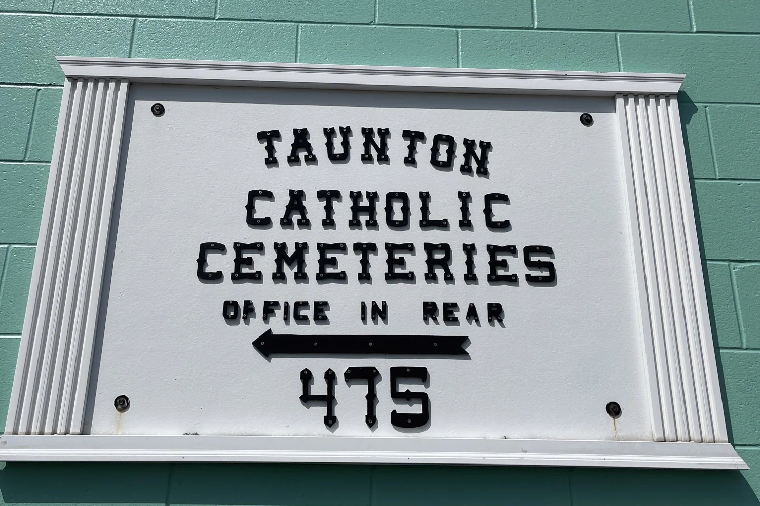 A sign saying "Tauton Catholic Cemeteries, Office in rear, 475" with an arrow pointing left